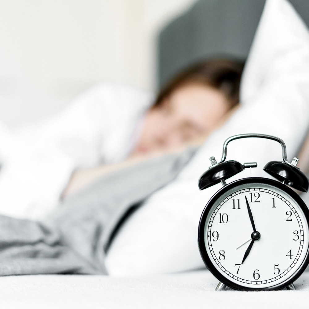 Frau im Bett mit Wecker