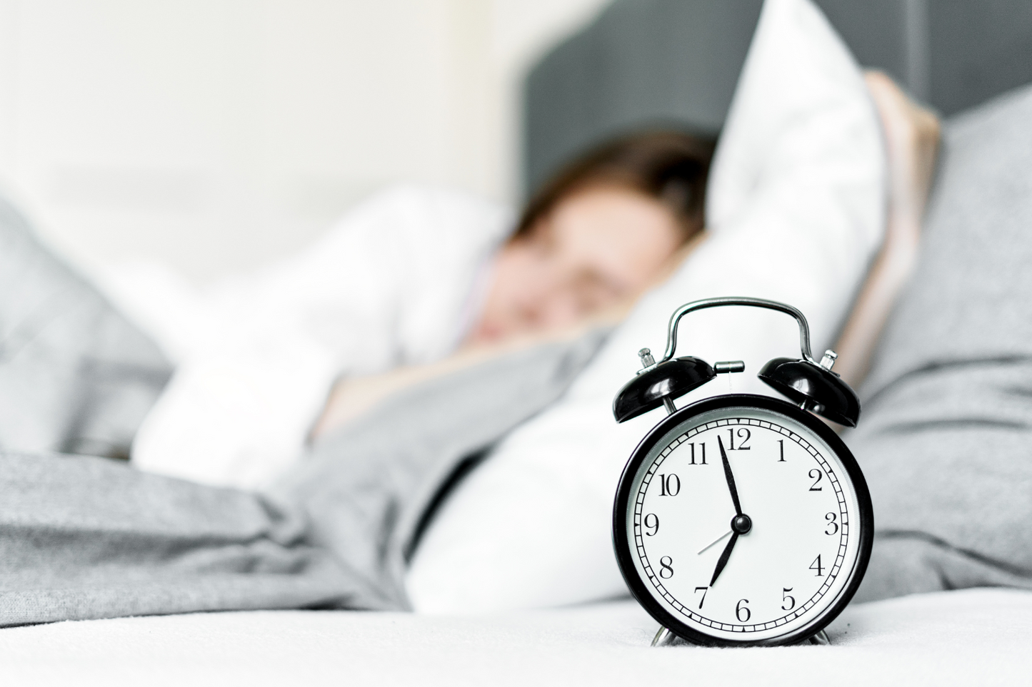 Frau im Bett mit Wecker