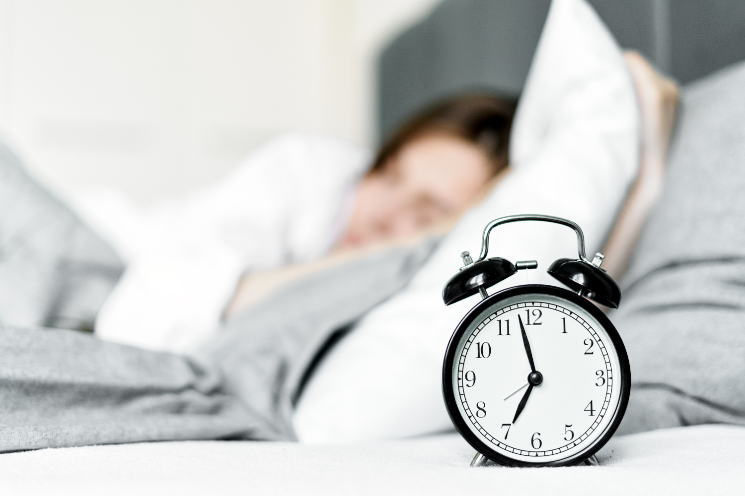 Frau im Bett mit Wecker