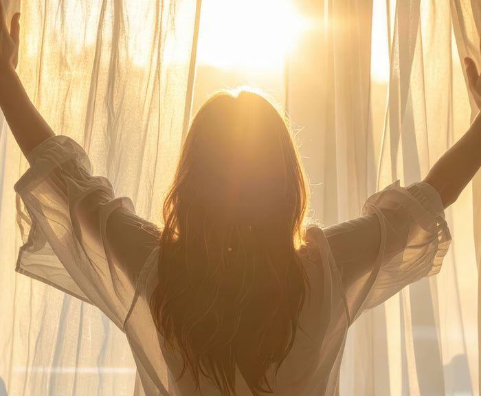 frau schaut aus dem Fenster in die sonne